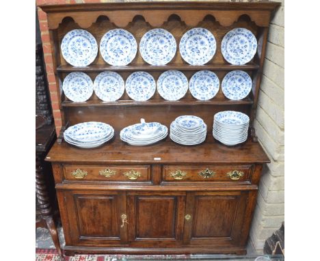 A George III oak dresser, the two tier open rack over two frieze drawers and a pair of cupboard doors flanking a fixed centre