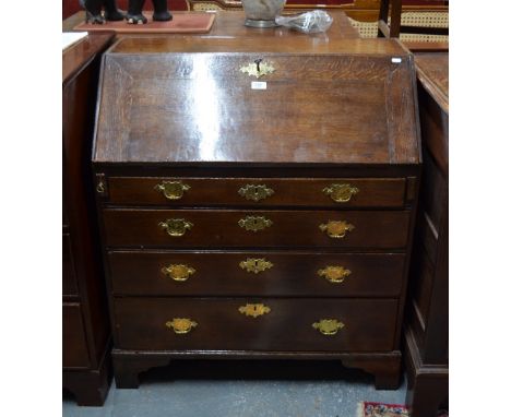 An 18th century oak bureau, the fall enclosing an interior of niches, drawers and a cupboard over four long graduated drawers