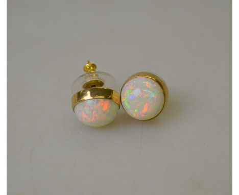 A pair of opal cabochon earrings of good colour and well matched showing multi-coloured flashes, 1 cm diam, yellow metal sett