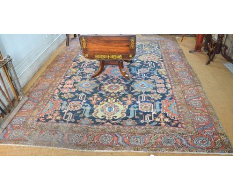 An antique Persian Heriz carpet, the all over design or geometric stylised flowers on blue ground, 3.10 x 2.40 m Condition Re