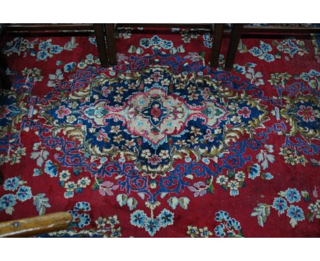 An old Persian Kirman carpet, the floral centre medallion on mid-red ground bordered by floral garlands, 378 x 252 cm