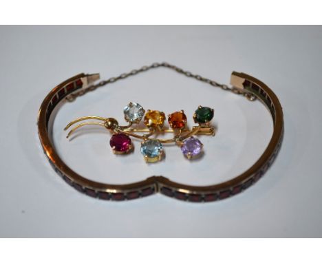 A multi-stone brooch in the form of flower spray to/w garnet set yellow metal bangle with concealed snap and fitted with safe