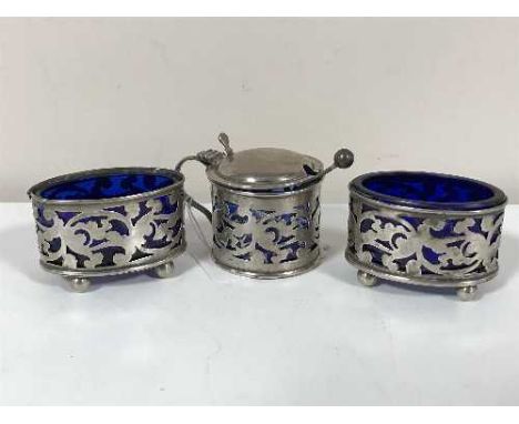 A silver three piece cruet set with blue glass liners and caddy spoon