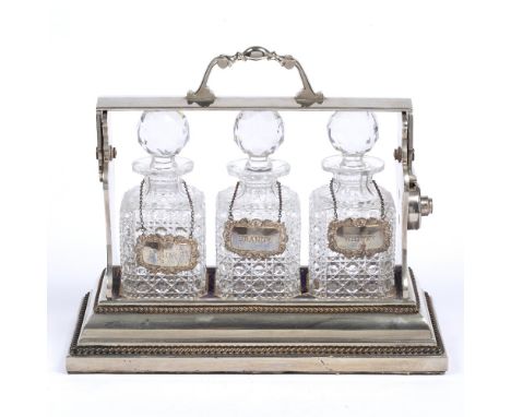 Silver plated three bottle tantalus Betjemann's Patent,&nbsp;with cut glass decanters and silver decanter labels,&nbsp;
