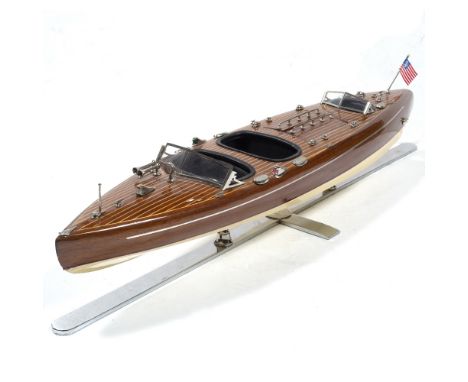 Riva model speedboat with wooden exterior and flag to the back, supported by a chrome or metal stand, 82.5cm across
