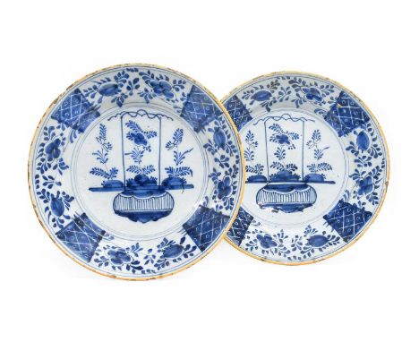 A Pair of Dutch Delft Chargers, circa 1750, each with yellow line borders and painted in blue with a basket of flowers under 