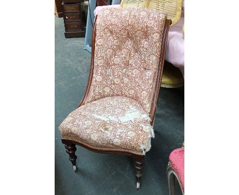 A button upholstered Victorian salon chair, mahogany frame, serpentine seat, on turned front legs with brass caps and ceramic