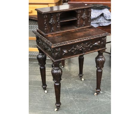 A carved oak occasional table, with a superstructure of shelves over a single drawer, 58x45x92cmH overall, ceramic casters 
