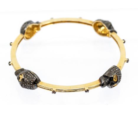 A diamond set silver gilt bangle, comprising four brown diamond set skull motifs, black rhodium plated, to a silver gilt bang