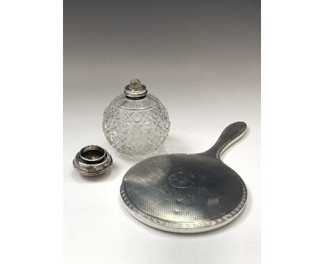 An engine-turned silver-mounted hand mirror, a Japanese cast white metal toilet jar with silver lid and a toilet jar 