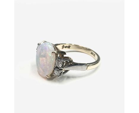 An 18ct gold ring, set an oval opal measuring 12.3x9.7mm to each side a pair of diamonds.