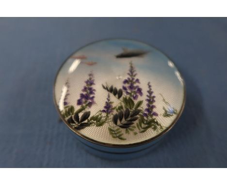 A hallmarked silver and enamel circular box, with pull off cover, the cover decorated with fish and flowers to a blue ground,