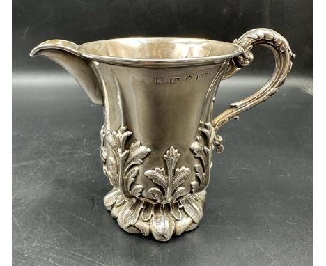 A Victorian silver embossed cream jug with floral design, indistinct hallmarks.