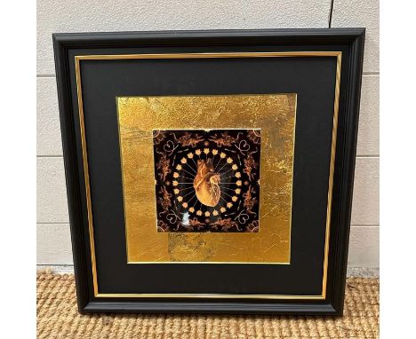 A framed decorative tile in gold and black with central anatomical heart 