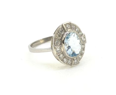 Platinum aqua and diamond cluster ring. The centrally set mixed cut oval aqua is in a rub over setting surrounded by 16 round