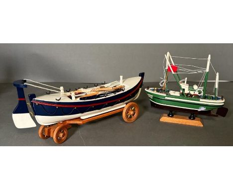 Two wooden painted scale model boats, a rowing boat on trailer and a fishing trawler on plinth 