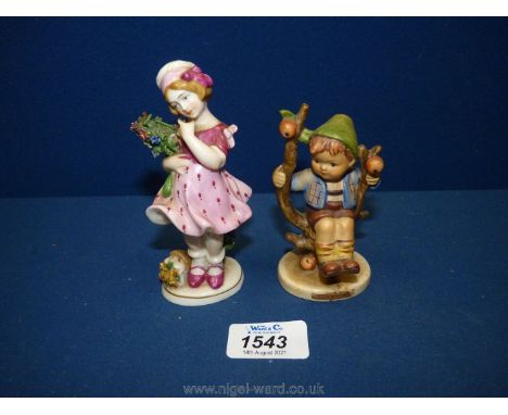 A West German Hummel figure of a boy on a branch and a young lady holding a bunch of flowers in a pink dress.