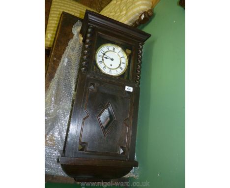 A darkwood framed wall clock, German made with Roman numerals on white, brass rings face the front of the case having barley 