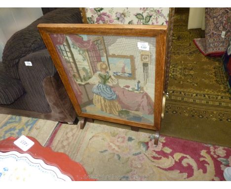 A glazed firescreen with tapestry of a young girl looking through a window