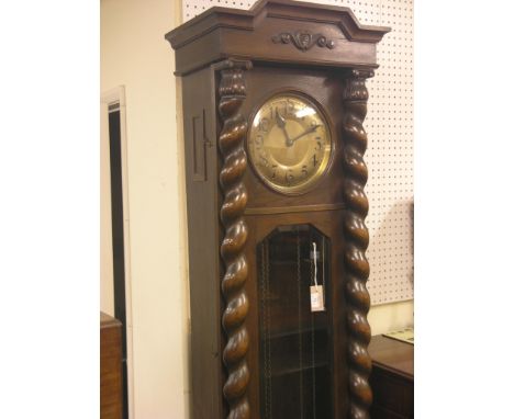 A 1920's dark oak longcase clock, with circular brass dial, chiming movement, case with bevelled glass trunk door and barley-