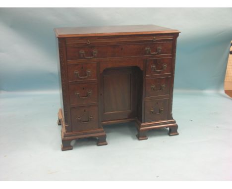 A George III mahogany kneehole desk, with brushing slide, one long and six short oak-lined drawers with original rococo brass