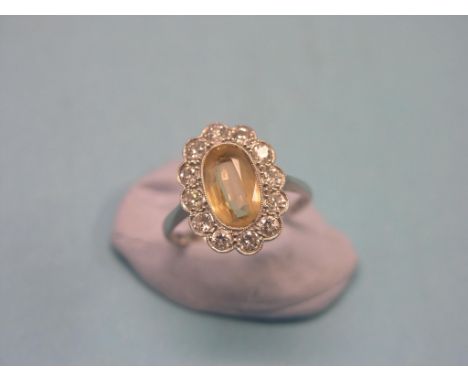 A white metal diamond dress ring, twelve small diamonds and central cut orange-yellow stone, size P SEE ILLUSTRATION