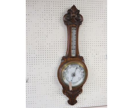 A late Victorian oak wheel barometer, with ceramic aneroid barometer and thermometer dials, case with carved detail, 34in. 