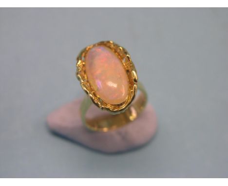 A gold dress ring, set large oval opal within gold nugget setting, size O, hallmarks indistinct