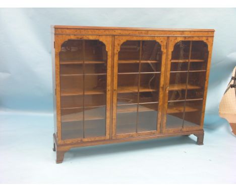 A burr-walnut veneered bookcase, nine adjustable shelves enclosed by three astragal-glazed doors, on bracket feet, 4ft. 6in.