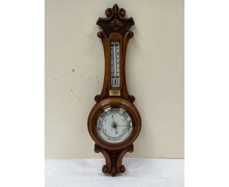 A Victorian oak carved aneroid barometer with thermometer scale. 24' high