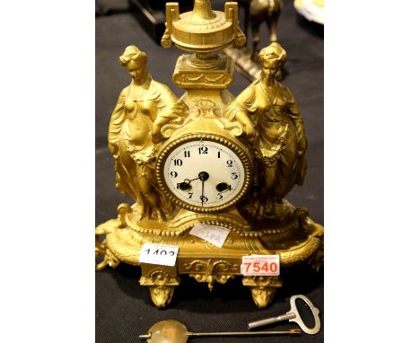 Antique gilt cast metal chiming clock depicting two Grecian ladies in full dress either side of the central pillar. Not avail