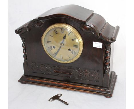 A stained oak mantel clock, the brass dial with Roman numerals denoting hours and outer chapter ring, the front decorated wit