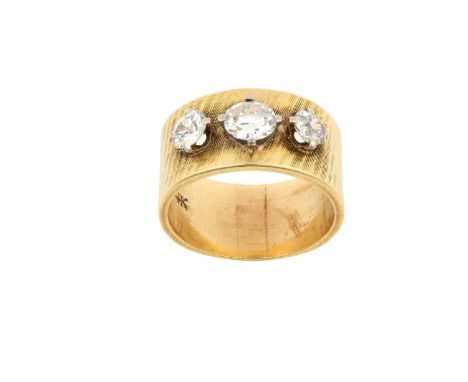 A Diamond Three Stone Ringthe graduated old cut diamonds in white claw settings, overlaid upon a broad yellow textured shank,