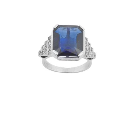 A Synthetic Sapphire and Diamond Ringthe emerald-cut synthetic sapphire in a white four claw setting, to stepped eight-cut di