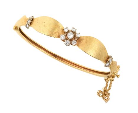 A Diamond Hinged Bangle the central round brilliant cut diamond cluster in white claw settings, to yellow textured shoulders 