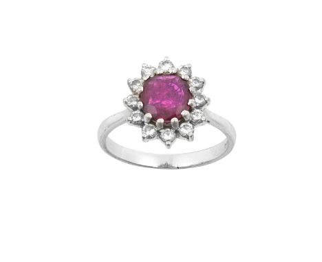 An 18 Carat White Gold Ruby and Diamond Cluster Ringthe oval cut ruby within a border of round brilliant cut diamonds, in cla