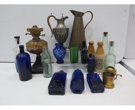 Mixed lot to include glass and stoneware bottles some with local interest, plus a hammered brass jug, oil lamp etc.