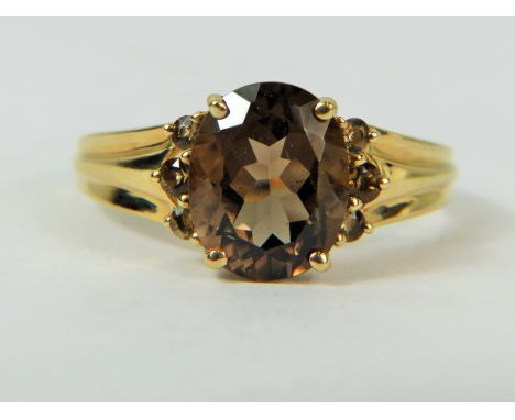 9ct Yellow Gold ring set with a Smokey Quartz stone measures approx 10 x 7 mm flanked each side by three clear CZ gemstones. 