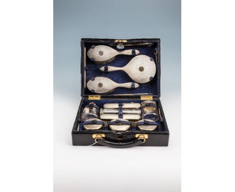 A SILVER TRAVELLING TOILETTE SET, contained in a black leather case, comprising hand mirror, pair of hair brushes, pair of cl