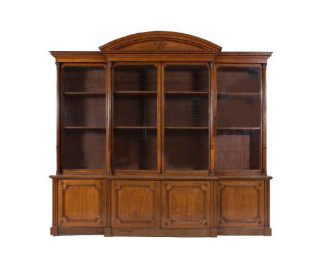 A VICTORIAN OAK BREAKFRONT BOOKCASE, the moulded dentil cornice centred by an arch above twin astragal glazed doors flanked b