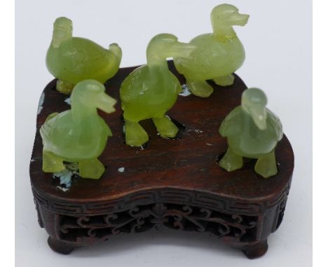 Five Chinese carved jade ducks on a carved fruitwood stand, a/f