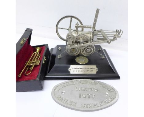 A small model of Richard Trevithick's steam locomotive, a novelty model of a trumpet and a Midland Railway Trust name plaque