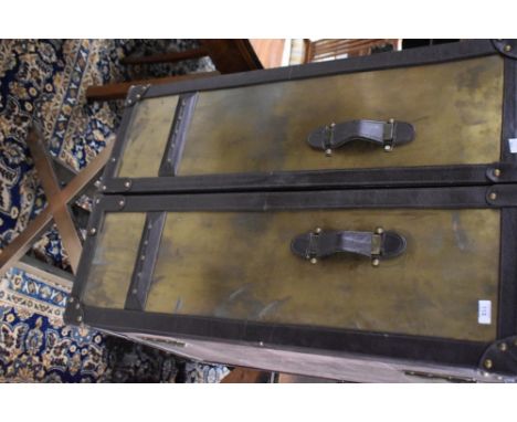 A reproduction steamer trunk on folding stand