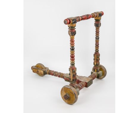  A charming Indian polychrome painted child's scooter the wooden frame bobbin turned with carved block ends, upon three small