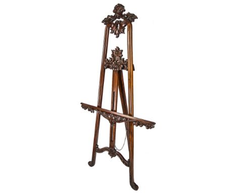  A Victorian mahogany easel the moulded, tapered frame with carved and pierced foliate decoration, conforming wing nut adjust