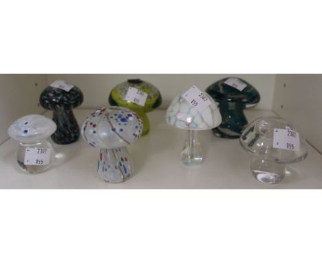 A shelf containing seven art glass paperweights including Phoenician examples