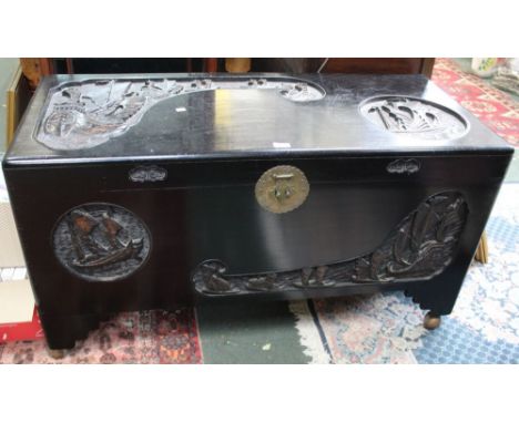 An ebonised carved oriental inspired wooden trunk, with later castors&nbsp;