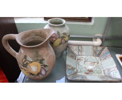 An earthenware decorated jug, together with a similar jug and a glazed ceramic bowl, decorated with a duck