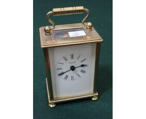 A "Dominion" brass cased carriage clock, having Roman numerals, the case on bun feet, with key