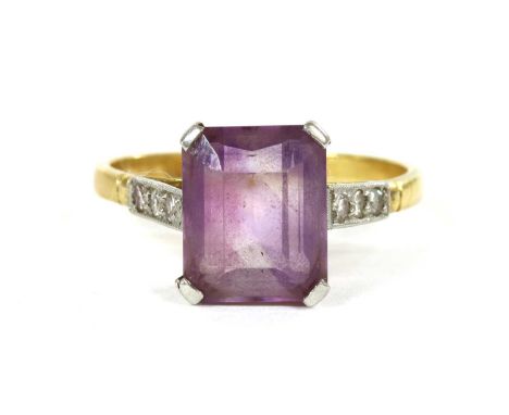 A gold amethyst and diamond ring, an emerald cut amethyst, claw set, to parallel shoulders grain set with a row of eight cut 